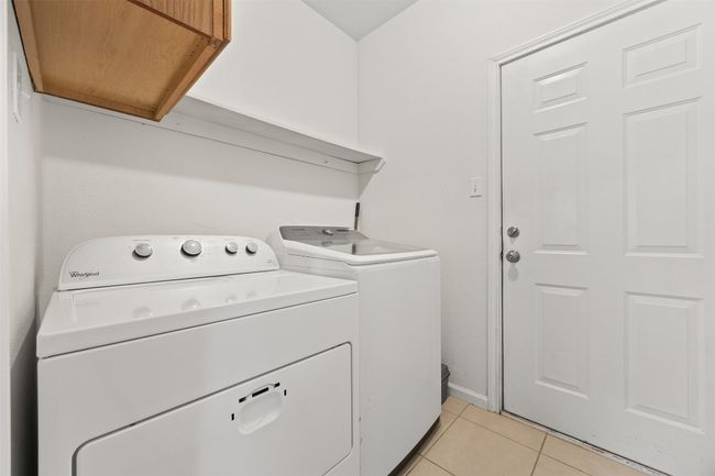 Laundry room with independent washer and dryer and light tile patterned flooring | Image 13