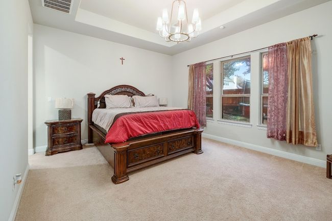 Bedroom with a tray ceiling, carpet, and a chandelier | Image 17