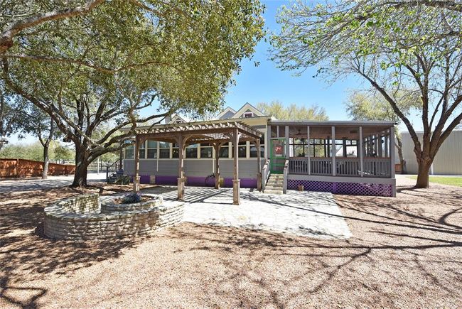 This view is looking at the rear of the Main house. Notice the firepit, pergola, screen room to the right and sunroom to the left. The gravel keeps the property very tidy. | Image 22