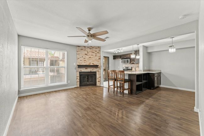Living room with dark wood finished floors, a ceiling fan, and a fireplace | Image 6