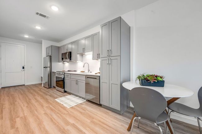 Kitchen with stainless steel appliances, gray cabinets, light wood-type flooring, light countertops, and tasteful backsplash | Image 7