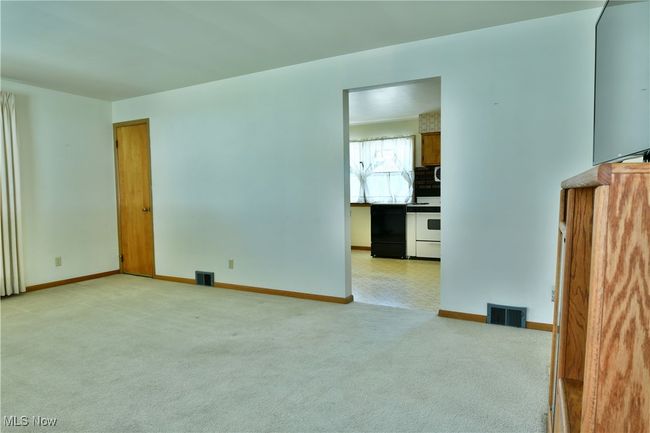 Unfurnished living room featuring baseboards, visible vents, and light colored carpet | Image 13