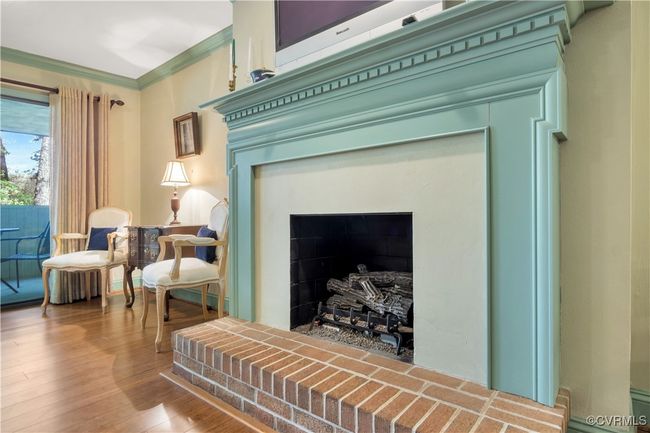 Details featuring wood finished floors, ornamental molding, and a fireplace with raised hearth | Image 15