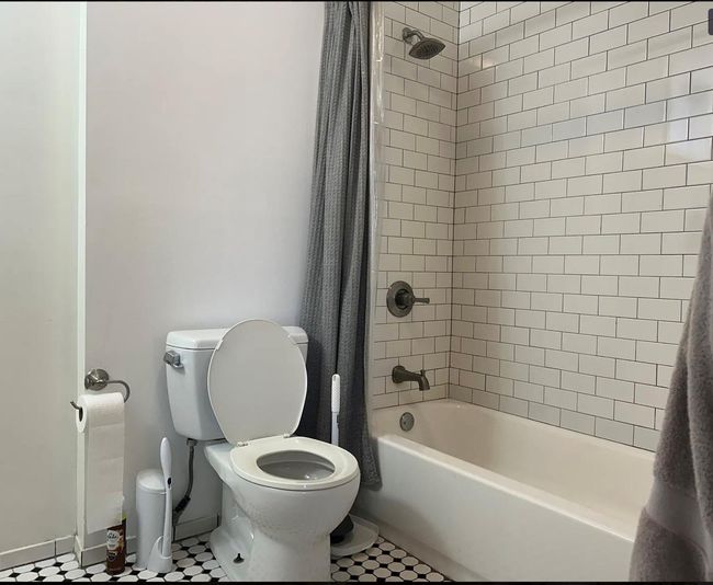 Bathroom featuring baseboards, shower / bath combination with curtain, and toilet | Image 7