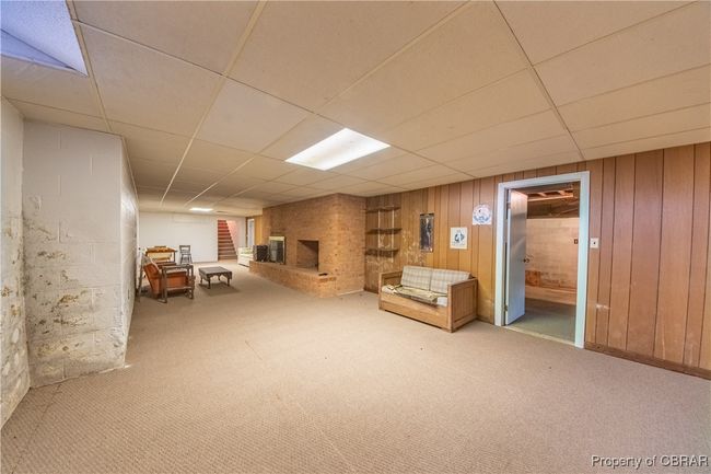 Basement with a drop ceiling, a fireplace, light colored carpet, and wooden walls | Image 30