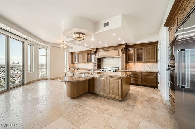 Kitchen featuring stone tile floors, tasteful backsplash, stainless steel appliances, baseboards, and light stone countertops | Image 12