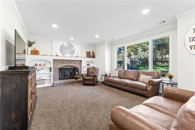 Living room featuring a brick fireplace, carpet, and crown molding | Image 3