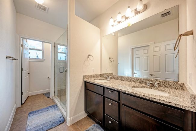Full bathroom with double vanity, a stall shower, tile patterned floors, and baseboards | Image 9