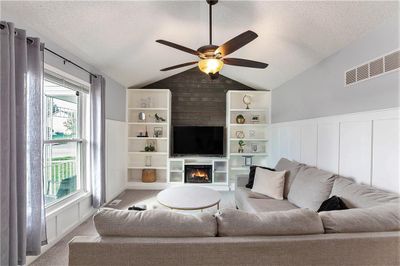 Living room with ceiling fan, light colored carpet, a textured ceiling, and vaulted ceiling | Image 1