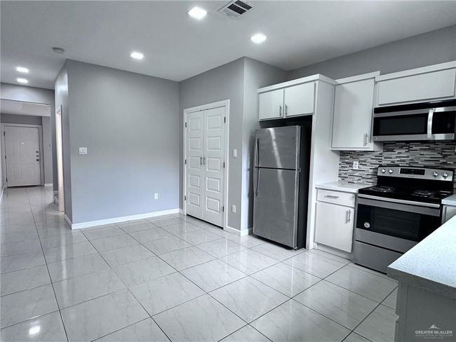 Kitchen featuring white cabinetry, tasteful backsplash, appliances with stainless steel finishes, baseboards, and visible vents | Image 7