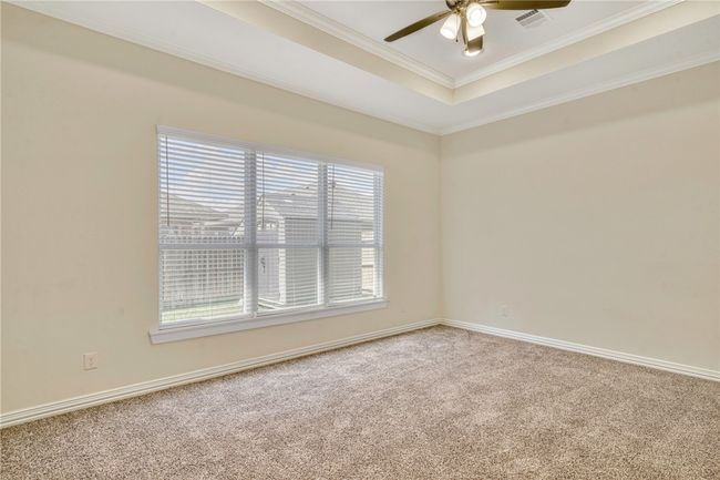 Carpeted empty room with ceiling fan, ornamental molding, and a tray ceiling | Image 15