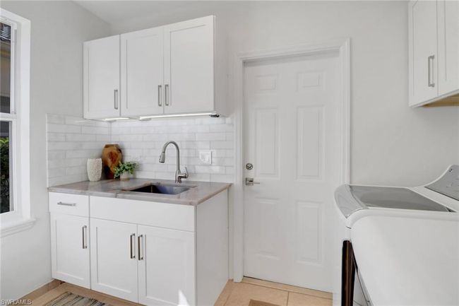Clothes washing area with a sink, cabinet space, and washing machine and clothes dryer | Image 26