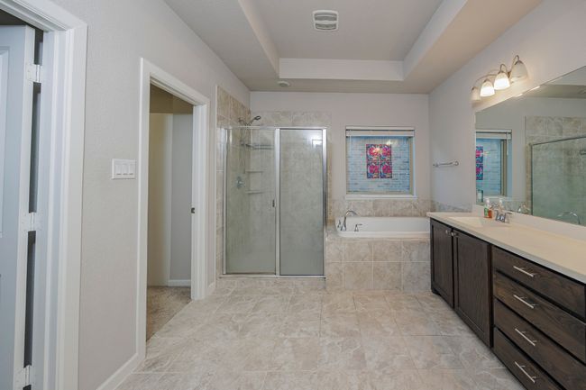 Bathroom with vanity, a garden tub, a tray ceiling, and a shower stall | Image 37