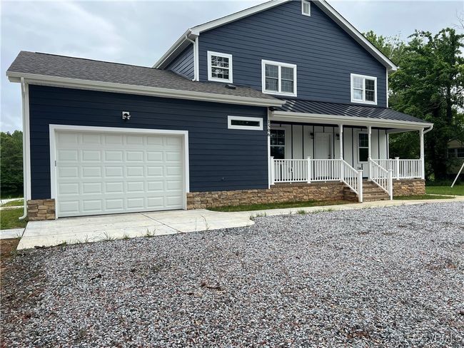 View of front facade with board and batten siding, a porch, a garage, and gravel driveway | Image 32