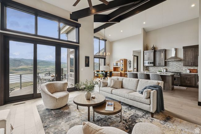 Living room featuring beam ceiling, high vaulted ceiling, light wood-type flooring, a ceiling fan, and a mountain view | Image 14