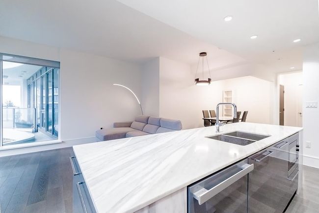 Kitchen with light countertops, wood finished floors, a sink, pendant lighting, and open floor plan | Image 9