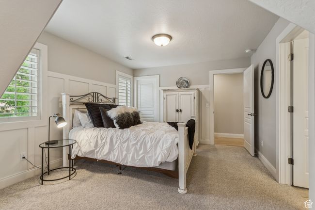 Bedroom featuring multiple windows, light colored carpet, and a decorative wall | Image 47