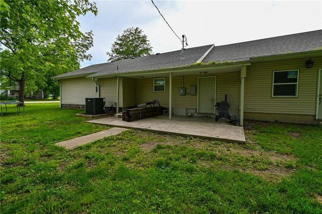Rear view of property with a trampoline, a patio area, cooling unit, and a yard | Image 39