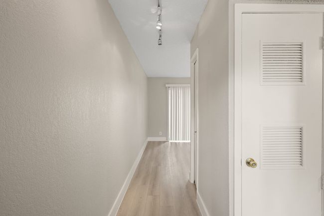 Hallway with light wood finished floors and track lighting | Image 16