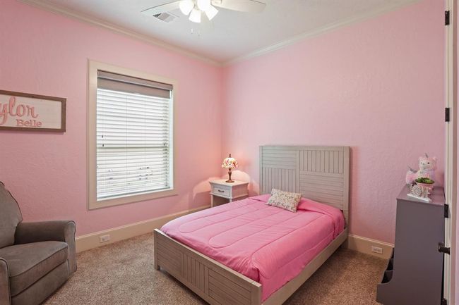 This Secondary Bedroom includes plush carpeting, crown molding, a 5-blade ceiling fan, and walk-in closet. It shares the full bath next-door with the fourth Secondary Bedroom down the hall. | Image 37