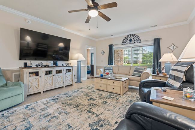 Living area with ornamental molding, light tile patterned floors, and a ceiling fan | Image 21