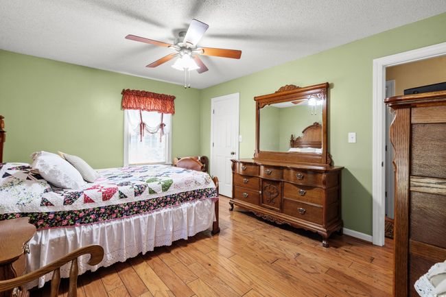 Bedroom featuring light wood-style floors, a ceiling fan, a textured ceiling, and baseboards | Image 10
