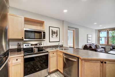 Kitchen with light brown cabinets, sink, appliances with stainless steel finishes, light hardwood / wood-style flooring, and kitchen peninsula | Image 2