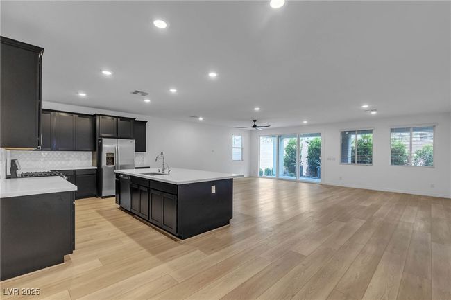Kitchen with appliances with stainless steel finishes, dark cabinetry, open floor plan, light countertops, and a sink | Image 8