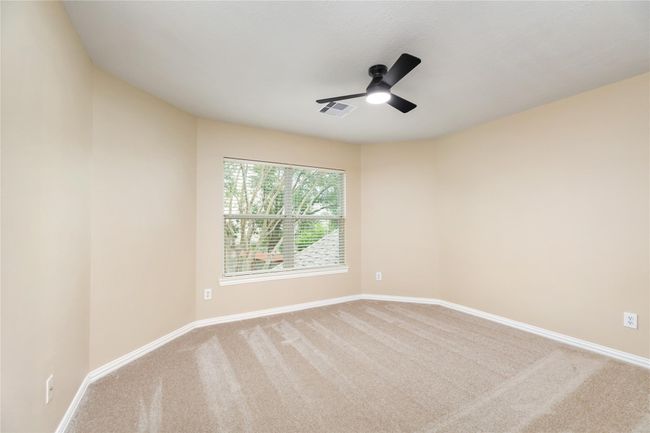 Unique, circular and spacious, this room features neutral-toned walls, fresh carpeting, and a ceiling fan. | Image 30