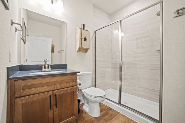 Bathroom with toilet, vanity, wood finished floors, and a stall shower | Image 28