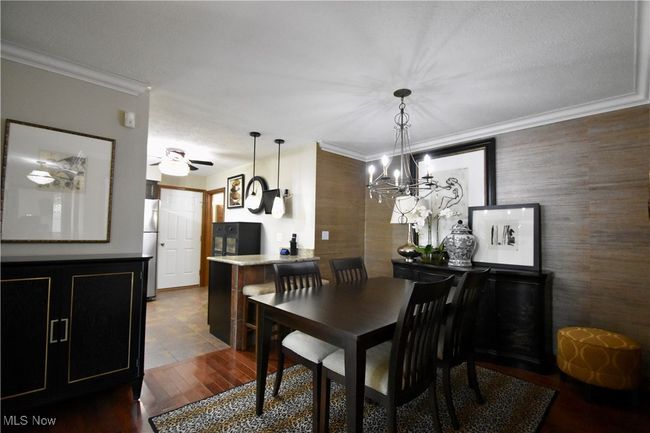 Dining space featuring ornamental molding, dark wood-type flooring, a chandelier, and ceiling fan | Image 10