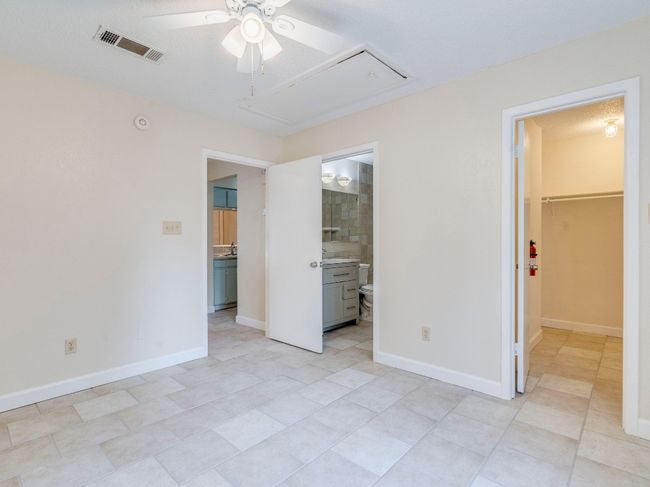 Unfurnished bedroom with attic access, a walk in closet, light tile patterned floors, and a closet | Image 11