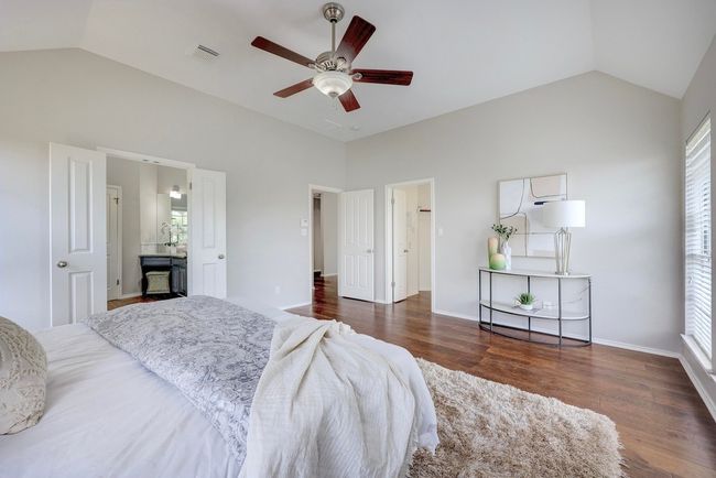 Bedroom with wood finished floors, high vaulted ceiling, ceiling fan, and ensuite bathroom | Image 22