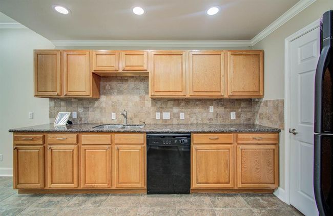 Spacious kitchen with elegant wood cabinetry, sleek granite countertops, and a convenient built-in dishwasher. Perfect for culinary creativity. | Image 7