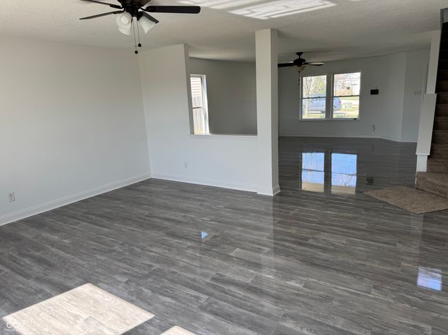 unfurnished living room featuring dark wood-style floors, baseboards, ceiling fan, and a textured ceiling | Image 8