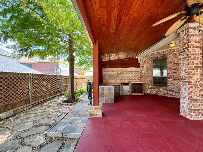 Fenced backyard featuring an outdoor kitchen, a ceiling fan, and a patio area | Image 39