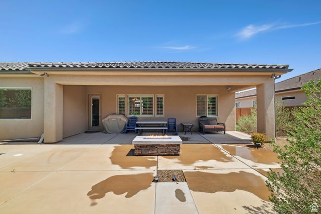 Back of house with stucco siding, a tile roof, a patio area, and an outdoor fire pit | Image 32