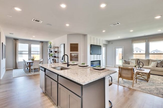 Kitchen featuring gray cabinetry, open floor plan, light wood-type flooring, light stone countertops, and recessed lighting | Image 4