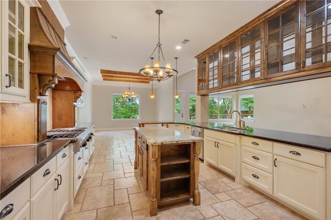 Kitchen with a sink, stone tile flooring, a chandelier, stainless steel appliances, and recessed lighting | Image 9