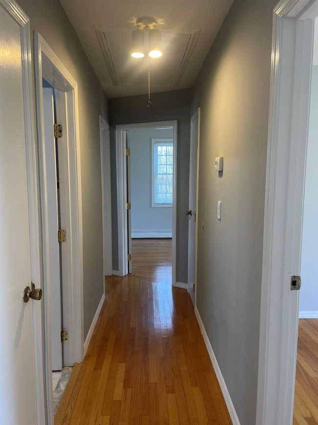 Hall with baseboard heating, light wood-style flooring, baseboards, and attic access | Image 20