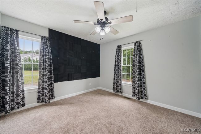 Empty room featuring carpet floors, healthy amount of natural light, ceiling fan, a textured ceiling, and baseboards | Image 22