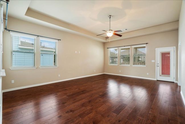 The large living room features wood flooring and tray ceilings. | Image 24