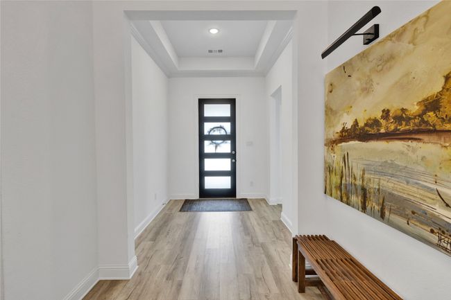 Foyer entrance featuring wood finished floors, a tray ceiling, and baseboards | Image 4