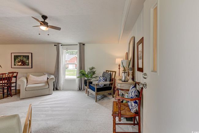 Living room featuring light colored carpet, ceiling fan, and a textured ceiling | Image 4