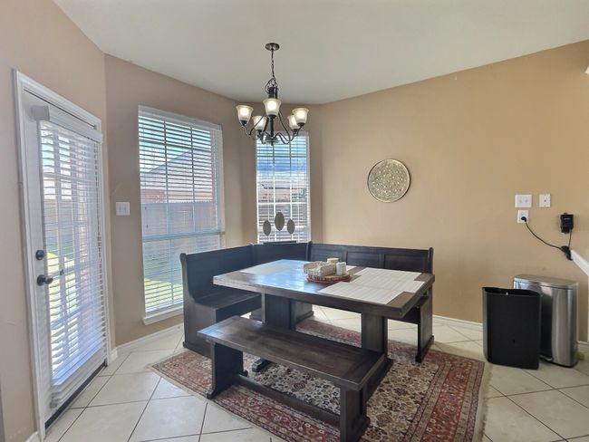 Dining room with a chandelier, light tile patterned floors, and baseboards | Image 6
