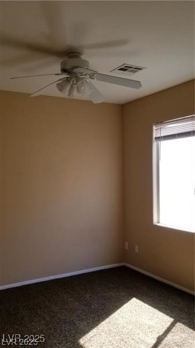 Empty room with ceiling fan and dark colored carpet | Image 31