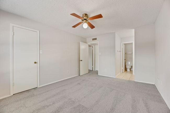 Unfurnished bedroom with carpet flooring, a textured ceiling, ensuite bathroom, and a ceiling fan | Image 15
