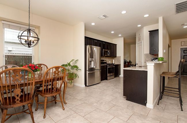 Kitchen with stainless steel appliances, a chandelier, tasteful backsplash, light stone counters, and recessed lighting | Image 5