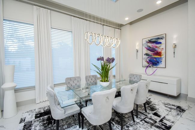 Modern formal dining room with large windows and a striking chandelier. | Image 15