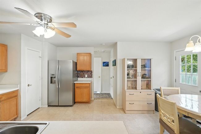 Kitchen with stainless steel fridge, light countertops, decorative backsplash, brown cabinetry, and ceiling fan | Image 13